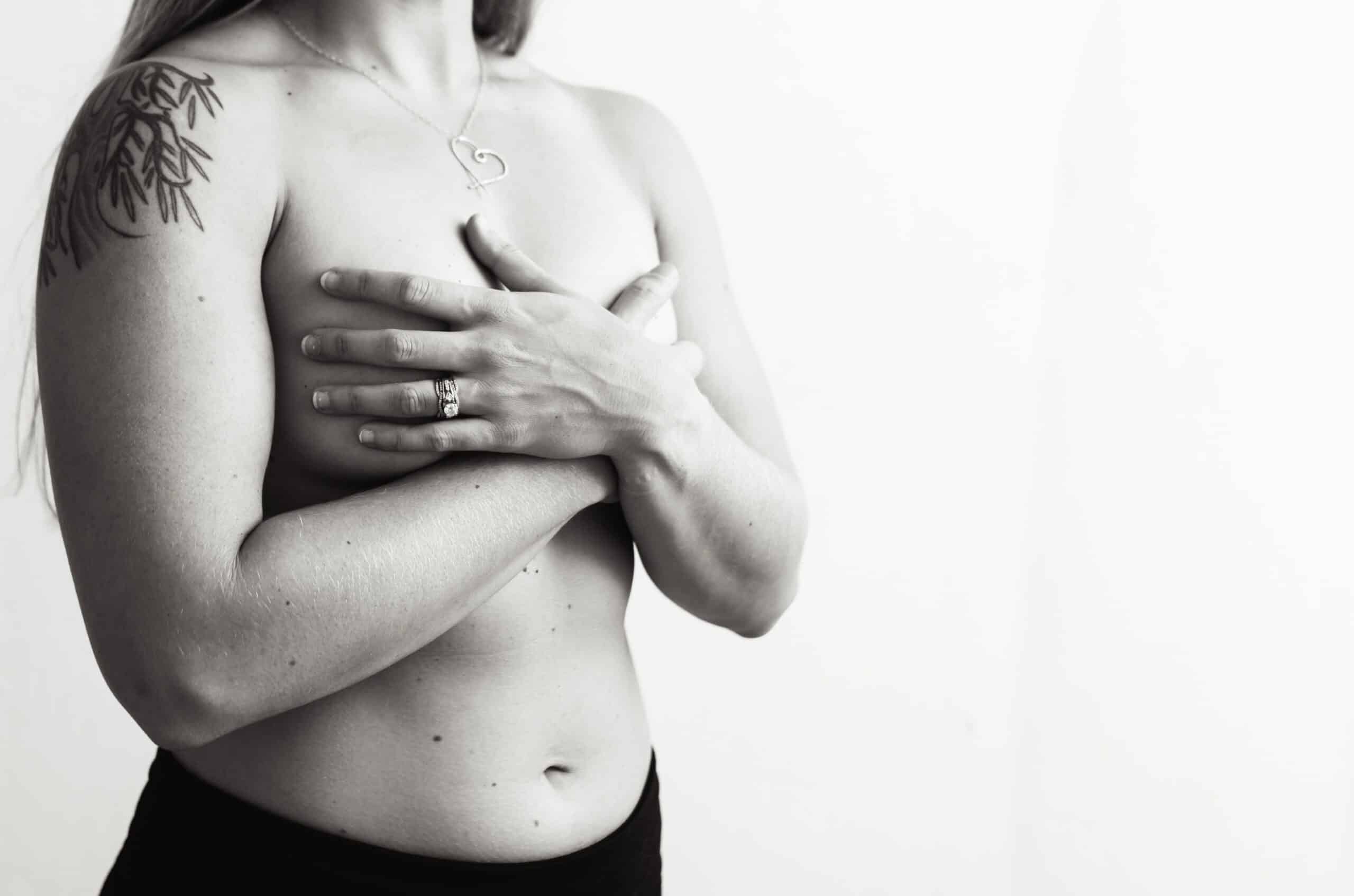 A black and white image of a woman crossing her hands over her breasts.